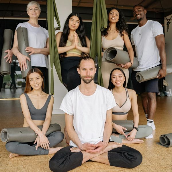 Diverse group of people smiling in a bright yoga studio.